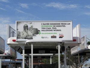 Image of an ad over a bus stop for the New Day Campaign Naloxone ad series with the quote "I saved someone from an overdose in minutes. You can, too. Naloxone works."